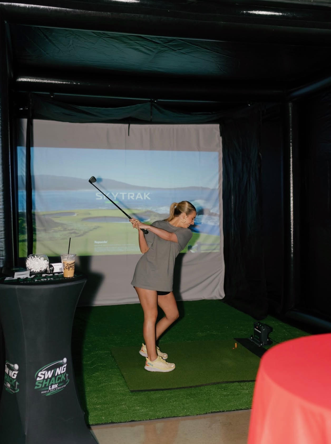 Guest taking a swing inside the Swing Shack LBK inflatable golf simulator
